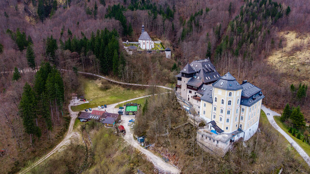 Aerial view of Klaus Castle and the nearby church nestled among dense forest on a hillside in Klaus an der Pyhrnbahn, Upper Austria, Austria.