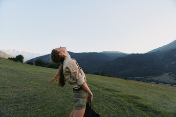 Fototapeta premium Cheerful woman lifestyle outdoor countryside portrait casual, nature, sunshine, mountains and meadow, relaxed pose, sunlit breeze, blue sky, authentic candid moment in nature