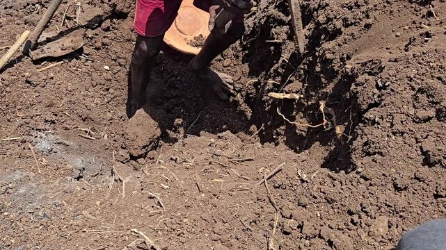 An aged worker digs parched land with a pickaxe under a blistering summer sun. The scene highlights the grueling manual labor and resilience amidst a sweltering energy crisis and intense heatwaves.