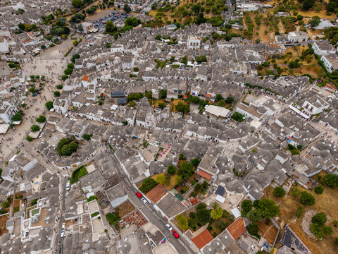 Aerial view of the historic Trulli houses with their iconic conical stone roofs and narrow streets crowded with tourists Alberobello, Apulia, Italy.