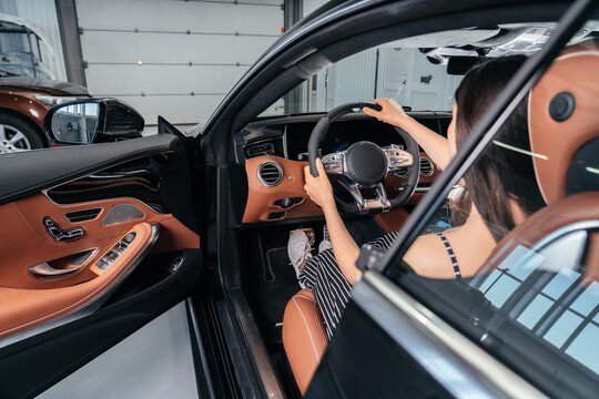 Young asian woman sitting in luxury car in garage before starting engine