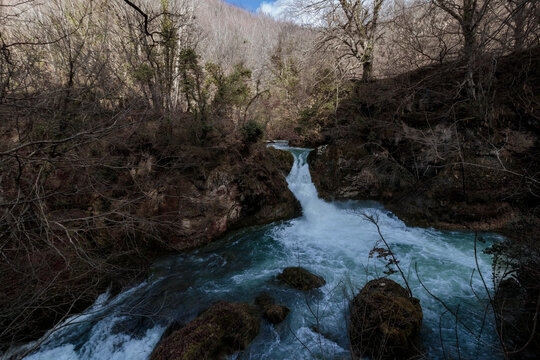 Vibrant river flowing through forest landscape with waterfall
