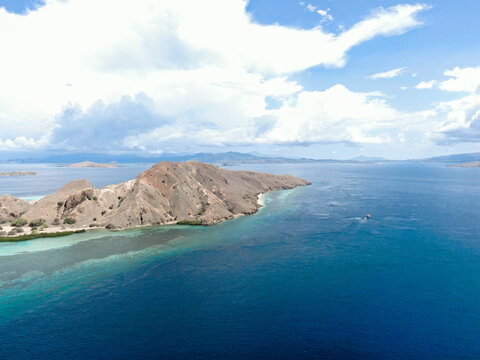 Scenic aerial perspective of Kelor Island with brown hills and clear blue ocean in Flores, Indonesia. Stunning tropical landscape of Komodo National Park for tourism and adventure marketing