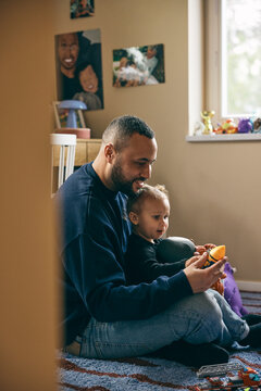 Smiling man spending leisure time playing with daughter in bedroom at home