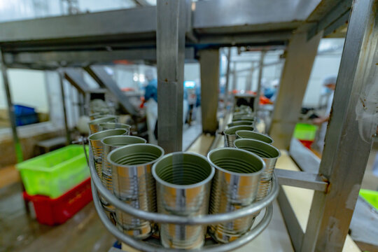 Canned fish are packed in cans before sealing. Ready-to-eat food on the production line in a canning factory. Background image of canned seafood production, produced by machines in the factory.