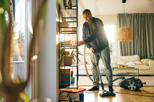 Full length of man doing household chores in living room