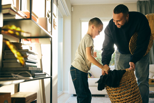 Father teaching son to collect dirty clothes in laundry basket at home