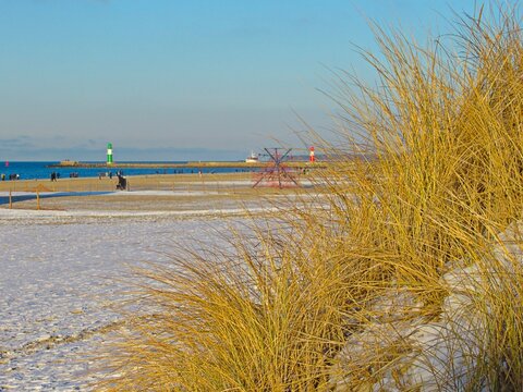 warnem&uuml;nde, deutschland - strand mit d&uuml;nen im winter und leuchtt&uuml;rmen im hintergrund