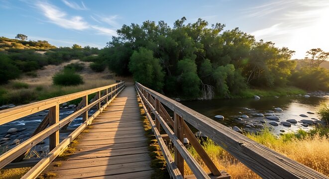 Rustic Wooden Footbridge Crossing Rocky River in Sunlit Natural Landscape