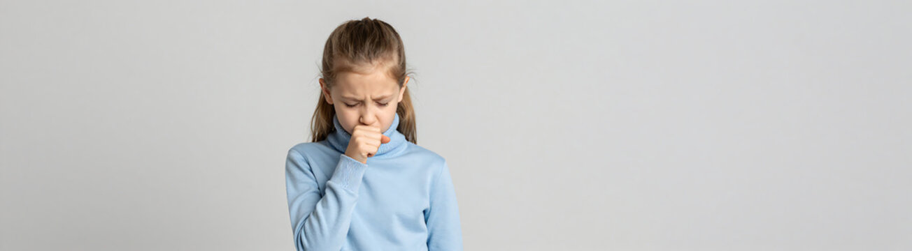 young girl light blue turtleneck stands minimalist space coughing bent elbow soft overhead lighting