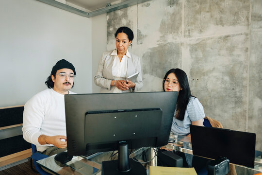 Young male and female employees sharing business ideas with investors at creative workspace
