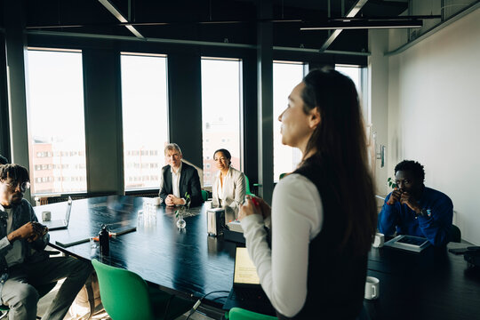 Group of coworkers listening to presentation from female entrepreneur at startup workspace