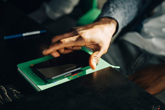 Close-up of businessman picking up smart phone from desk at office