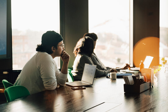 Side view of male entrepreneur attending team meeting with coworkers at office