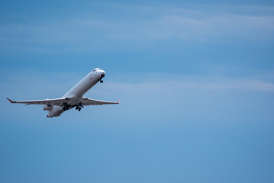 White regional jet aircraft climbing against clear blue sky