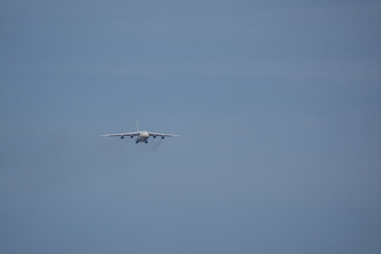 Large heavy cargo aircraft approaching through hazy overcast sky