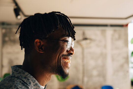 Side view of happy businessman with dreadlocks at modern startup office