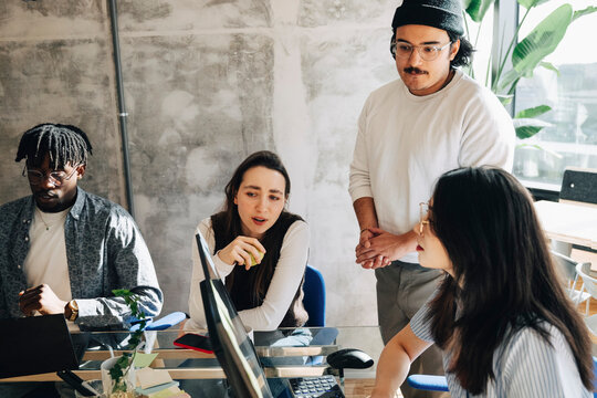 Group of entrepreneurs discussing strategies while working together at startup workspace