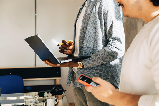 Male business professionals holding wireless technologies at creative workspace