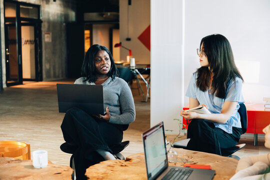 Female entrepreneur having conversation with team at modern startup office