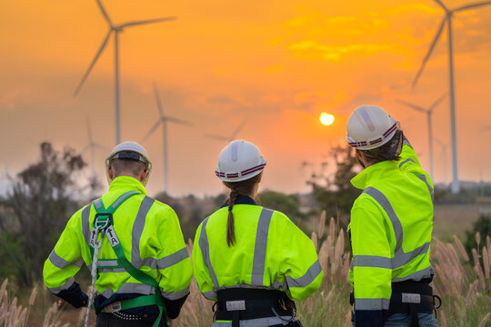 Team Engineers men and woman checking and inspecting on construction with sunset sky. people operation. Wind turbine for electrical of clean energy and environment. Industrial of sustainable.