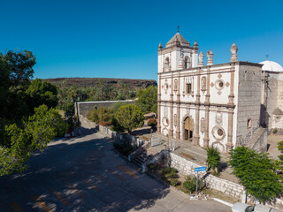 Obraz premium Mission Church stands in San Ignacio, Baja California Sur. Surrounding trees and roads can be seen in the bright sunlight