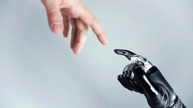 Human hand reaching out to touch fingers with a robotic bionic hand