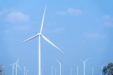 Fototapeta premium White wind turbines against a clear blue sky, symbolizing clean energy and sustainable technology.