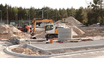 Prace ziemne i montażowe na placu budowy przy użyciu koparki kołowej w pobliżu betonowych elementów kanalizacyjnych. © tomo81