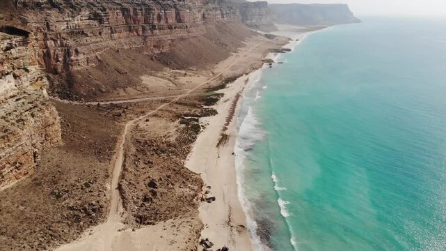 Panoramic aerial video of Socotra Island's rugged coastline, where desert cliffs meet the turquoise ocean, perfect for travel and adventure footage