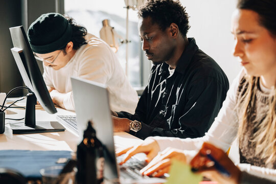Group of focused programmers working on computers at desk in office