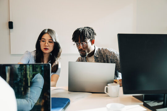 Group of male and female programmers working together on laptop at modern startup office