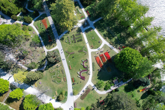 Aerial view of Parc de l'Independance with vibrant tulip flower beds, lush green trees, and people walking along paths in Morges, Vaud, Switzerland.