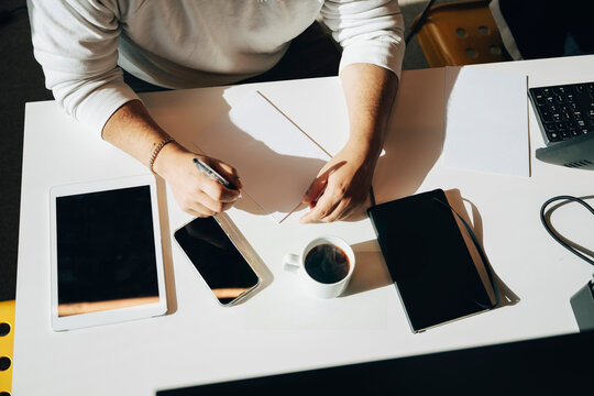 High angle view of businessman writing notes on paper at white desk