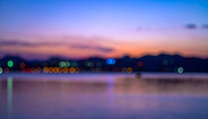 Fototapeta premium Blurred waterscape at dusk with bokeh lights reflecting on calm surface