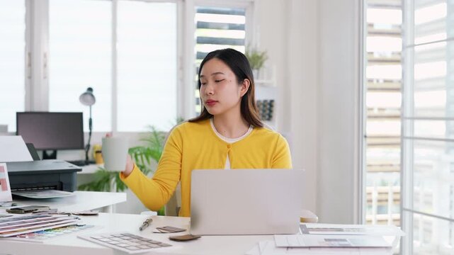 Asian woman interior designer at modern office desk considering document in morning. Happy female architect work with paperwork use laptop working on a project at workplace.
