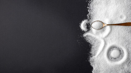 Top view of spilled sugar scattered across deep black background, creating striking contrast and minimalist composition. Large empty copy space for product placement or advertising text.  © magdal3na