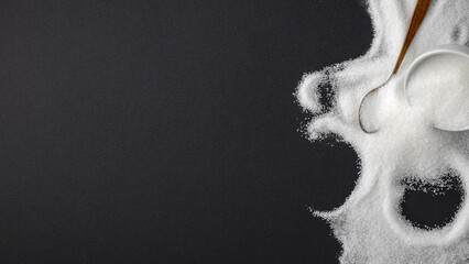 Top view of spilled sugar scattered across deep black background, creating striking contrast and minimalist composition. Large empty copy space for product placement or advertising text.  © magdal3na