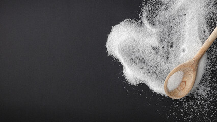 Top view of spilled sugar scattered across deep black background, creating striking contrast and minimalist composition. Large empty copy space for product placement or advertising text.  © magdal3na