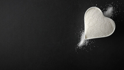 Top view of spilled sugar scattered across deep black background, creating striking contrast and minimalist composition. Large empty copy space for product placement or advertising text.  © magdal3na
