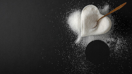 Top view of spilled sugar scattered across deep black background, creating striking contrast and minimalist composition. Large empty copy space for product placement or advertising text.  © magdal3na
