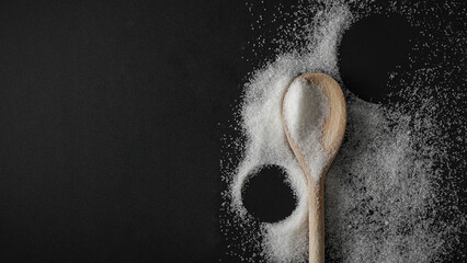 Top view of spilled sugar scattered across deep black background, creating striking contrast and minimalist composition. Large empty copy space for product placement or advertising text.  © magdal3na