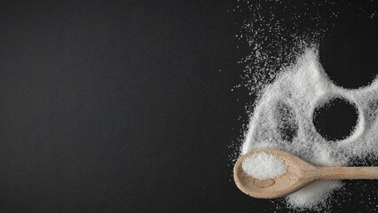 Top view of spilled sugar scattered across deep black background, creating striking contrast and minimalist composition. Large empty copy space for product placement or advertising text.  © magdal3na
