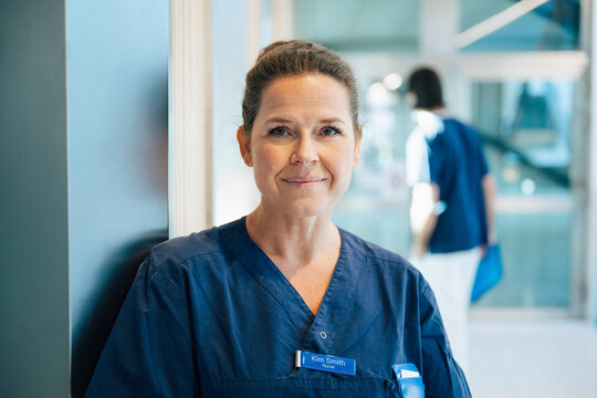 Thoughtful female healthcare expert wearing uniform standing in hospital corridor