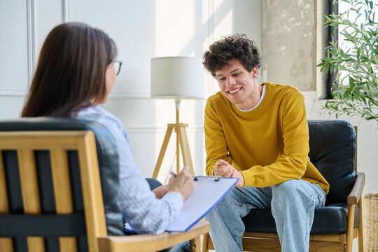 Happy teenage boy smiling during successful consultation with female psychologist