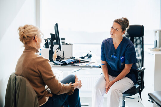 Female medical expert interacting with senior patient during visit in hospital