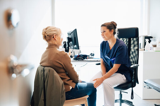 Supportive female healthcare professional talking with senior woman during medical visit in hospital