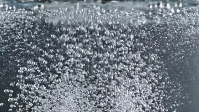 Close-up of countless small, shimmering air bubbles rising through clear liquid, creating a dynamic and refreshing effervescent effect