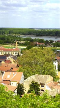 Panorama of Sremski Karlovci with baroque bell tower above historic rooftops and Danube beyond. Shows river corridor heritage towns, preserved European architecture, and slow cultural travel routes.