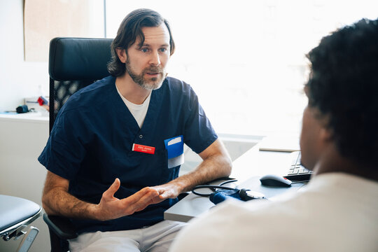 Male medical expert advising young man during his visit in hospital room